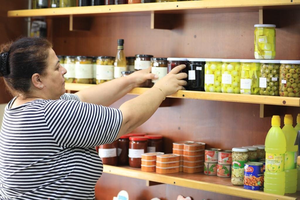 A shop owner stocking shelves at Mini Market C&C, a shop supported in Phase 1
